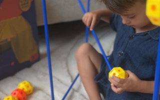 Kind dat vrolijk experimenteert met constructiespeelgoed en zo creativiteit en probleemoplossend vermogen ontwikkelt.